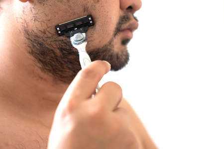 Close up of young man shaving his face using soap and cream in the morningの写真素材