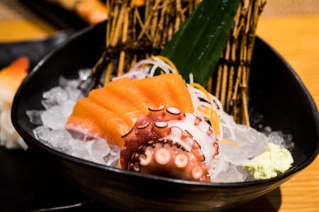 Salmon sashimi and octopus tako sashimi served on ice in black bowl. Japanese foodの写真素材