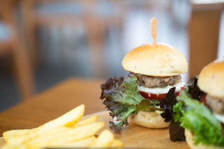 Elegant mini burgers served with french fries on wooden plate