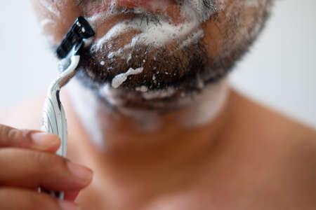 Morning routine. Young man shaving his faceの写真素材