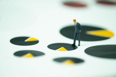 Miniature businessman in suit standing on performance graph. Using as work report, management profit and loss of company achievement and analysis.の写真素材