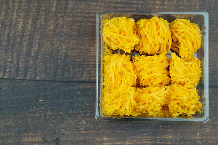 Crispy Thai sweetmeat made of egg yolk Thai name is Foi-Thong in box on wood background