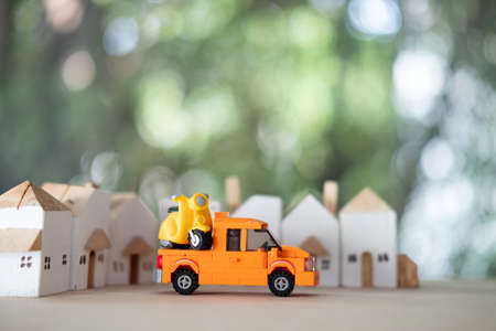 Miniature motorcycle on orange pickup truck with home background, service of move to fix. Concept of maintenanceの写真素材