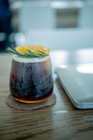 Orange juice mix espresso shot and ice with laptop on wooden table. Office desk table