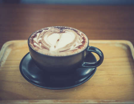 Hot chocolate latte art in black cup. Heart shape art foam texture top view.の写真素材