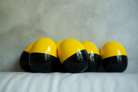 Plastic of yellow and black egg shape on sofa. Concept of surprise toy