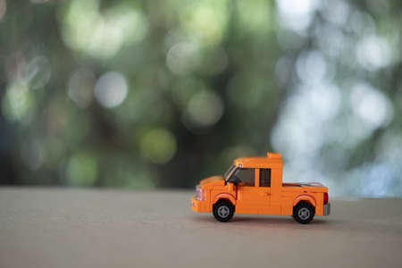 Miniature orange plastic toy car on wood table, pickup truckの写真素材