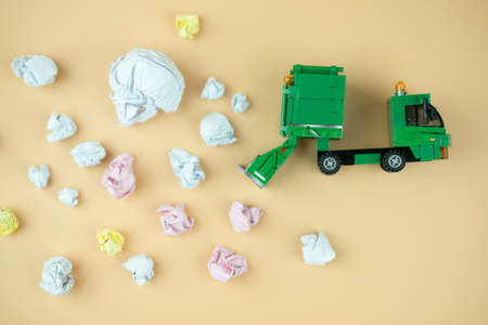 Miniature of crumpled office paper and miniature green plastic garbage truck. New idea conceptの写真素材