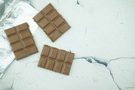 The chunks of broken dark chocolate bar on white marble background.の写真素材