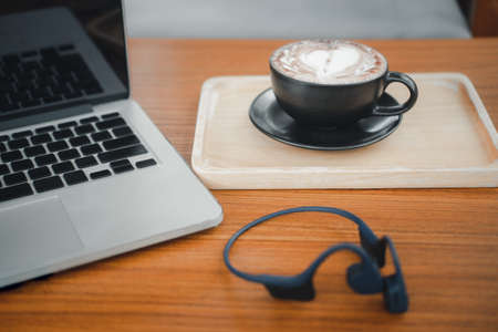 A cup of hot dark chocolate on wooden table with  laptop. Drink for hot drink break after working or weekend meeting. Office desk tableの写真素材