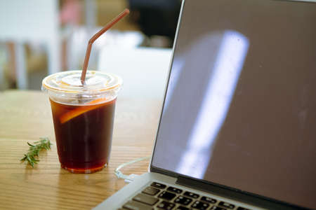 Black iced coffee with a notebook on wood table. Coffee break beverage cafe drinking enjoyment...