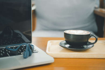 A cup of hot dark chocolate on wooden table with  laptop. Drink for hot drink break after working or weekend meeting. Office desk tableの写真素材