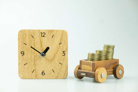 Stock of gold coins in toy train and wood watch. Concept of time is moneyの写真素材