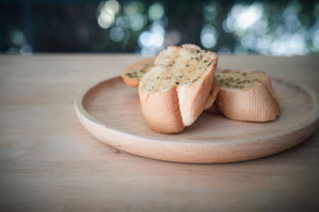 Wooden plate with delicious homemade garlic bread on wooden table