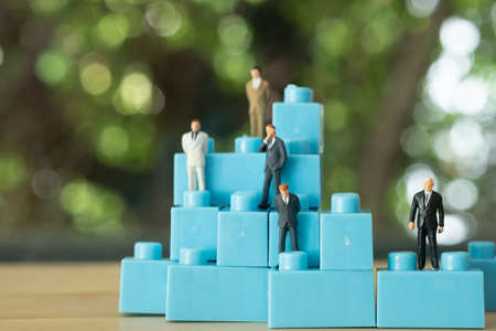 Miniature businessman standing on blue block. Success business management growth business concept....