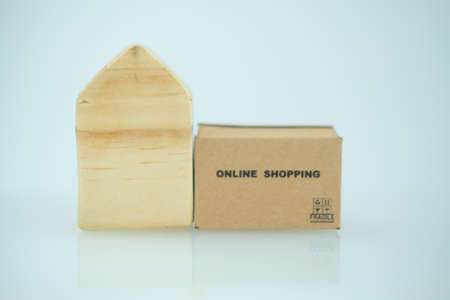Miniature brown box and miniature home. Promote stay at home and shopping online. Coronavirus, covid-19, shopping online, stay home concept.の写真素材
