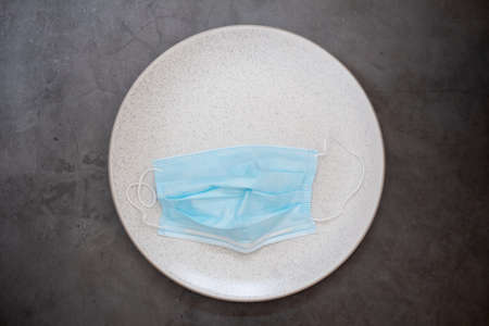 Coronavirus prevention medical surgical masks on white dish. Top view.の写真素材