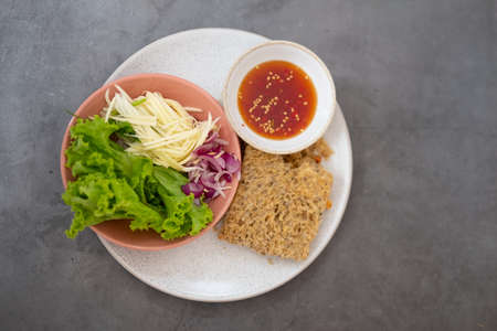 Crispy catfish spicy salad with sliced mango, shallot and lettuce. Thai cuisine