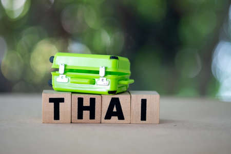 Miniature suitcase on woodn blacks word of Thai. Concept of travel in Thailand.の写真素材