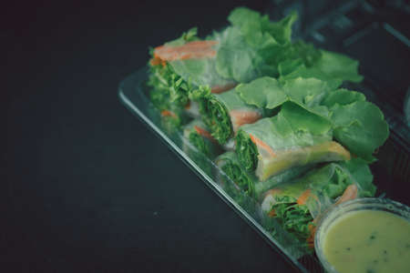 Salad roll vegetables wrapped in flour with salad dressing on clear plastic boxの写真素材