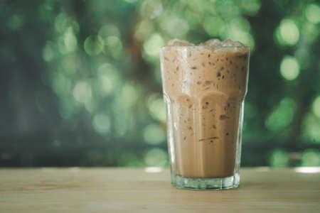 Cold coffee with ice in glass on wood tableの写真素材