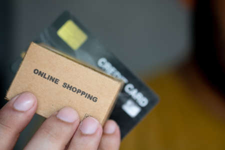 Hands holding credit card and miniature brown cardboard box online shopping. Concept of online shoppingの写真素材