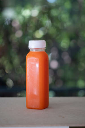 One plastic bottle with tasty carrot juice on wood tableの写真素材