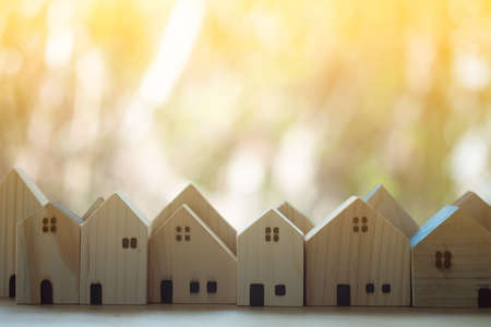 Building different wood house model on light nature background. Managing property investment conceptの写真素材