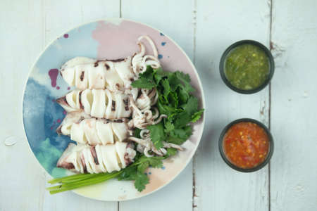 Close up of steamed squid served with coriander and eating with spicy seafood sauceの写真素材