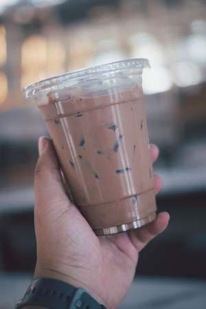 Hand holding the plastic cup of cold Mocha coffee. Close upの写真素材