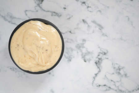 Bowl of cream dressing sauce on marble tableの写真素材