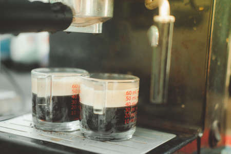 Two cups of espresso poured from a professional espresso machine. Espresso machine brewing a coffee espressoの写真素材