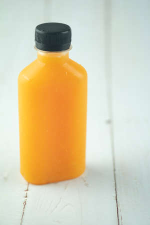 One bottle with tasty drink of orange juice on wood tableの写真素材