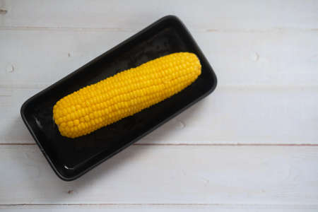 Fresh of yellow cob boiled corn put on black trayの写真素材