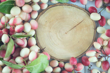 Top view empty of round wooden tag with fresh Carissa carandas. Flat lay. Carandas-plum or Karonda fruit (Carissa carandas L.)の写真素材