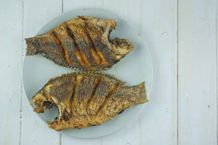 Thai food deep fried Tilapia fish on plate on wooden background.の写真素材