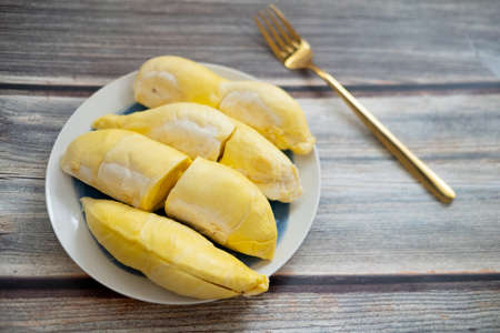 Fresh durian (monthong) on dish and wood background. King of fruit from Thailand on summer season