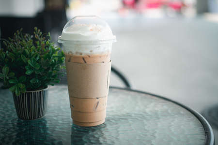 Iced coffee latte decoration with milk froth in plastic glass in coffee shopの写真素材