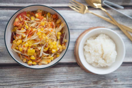 Somtum corn salad served with sticky rice delicious food in Thailand on wooden table