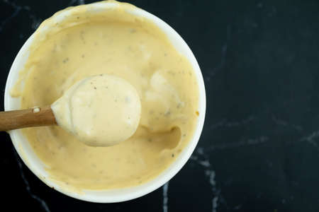 Use wooden spoon scoop of caesar salad dressing from white bowlの写真素材