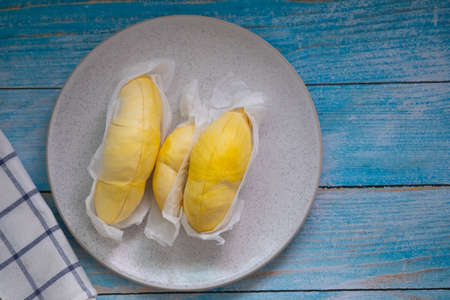 Fresh Durian and pulp of Durian yellow color on white dish on blue wooden backgroundの写真素材