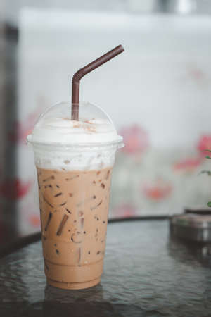 Iced coffee latte with drinking straw on table at coffee shopの写真素材