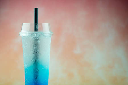 A long plastic glass with blue italian soda drink on a pastel background. Summer drinkの写真素材