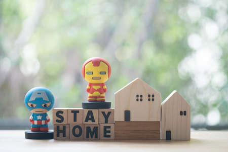 Bangkok, Thailand - June 9, 2020: Superhero with miniature wood home. Concept of hero at home. Concept of stay home to reduce risk of infection and spreading the virus. Stay safe, stay inside home.のeditorial素材