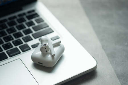 Bangkok, Thailand - June 10, 2020: Airpods put on Apple Macbook Pro. Trendy office and freelance workplace. Top view.のeditorial素材