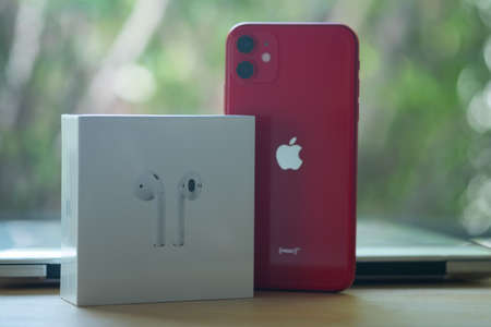 Samut Prakan, Thailand - June 18, 2020 : Apple iPhone 11 PRODUCT RED and Airpods in box on wood tableのeditorial素材