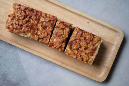 The square slice of toffee cake with cashew nut on wooden tray