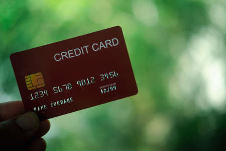 Image of man holding red credit on blur nature backgroundの写真素材