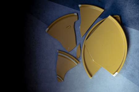 Shards of a broken yellow dish.  Metaphor of family quarrel.の写真素材
