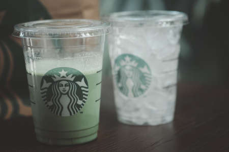 Samut Prakan, Thailand - June 21, 2020: Cup of iced green tea latte at Starbucks Coffee shop and ice in glass for takeaway on tableのeditorial素材